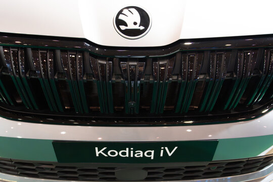 LISBON, PORTUGAL - MAY 16, 2026: Symmetrical close-up of the traditional winged arrow logo, gloss black textured grille, and Kodiaq iV model plate on a white hybrid SUV at the ECAR Show exhibition