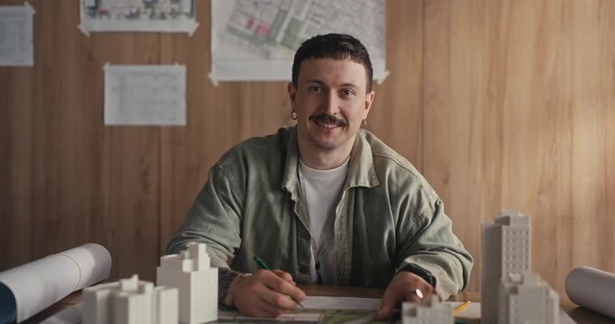 Architect sketching plans at a desk in a modest office