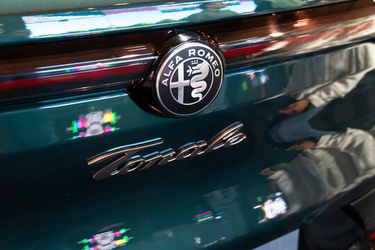 LISBON, PORTUGAL - MAY 16, 2026: Angle close-up view of the classic circular Alfa Romeo badge and Tonale cursive script lettering on glossy emerald green tailgate at ECAR Show hybrid car exhibition