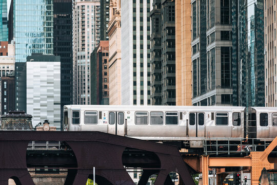 Commuter train passing on elevated railway bridge in downtown Chicago city center. Urban transit, transportation infrastructure, metropolitan commute and public travel concept.