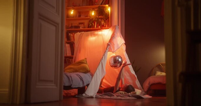 Glowing indoor teepee tent in a cozy home room with blanket and cushions