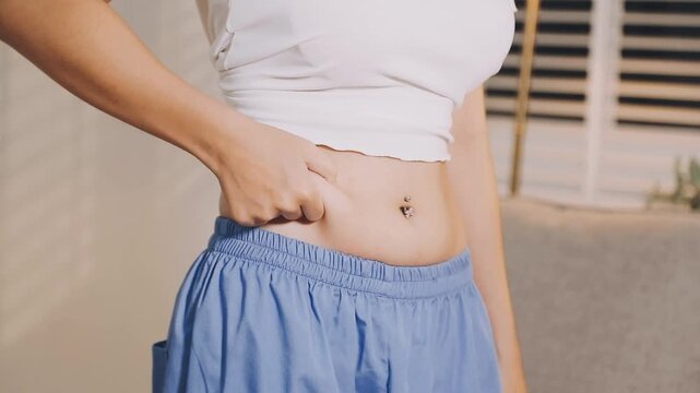 woman's hand holding excessive belly fat, overweight concept