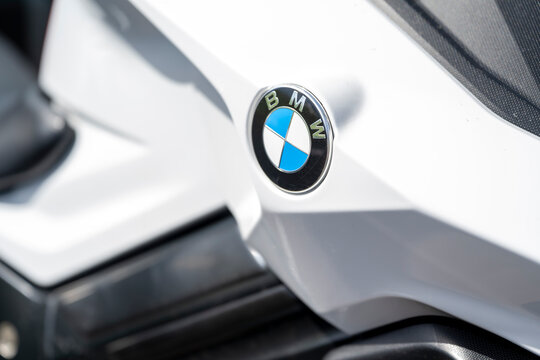 Close-up detail of a BMW emblem on a white motorcycle bodywork with shallow depth of field. Editorial use only.