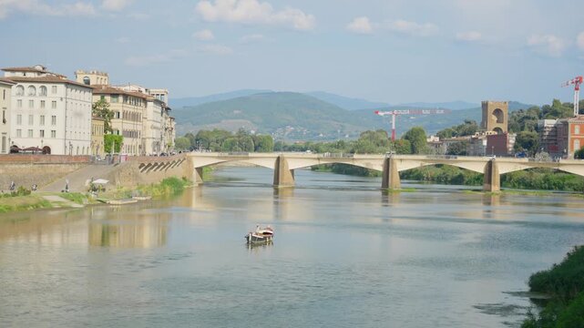 Scenic view of Ponte alle Grazie bridge over the Arno River in Florence, Italy. Elegant city architecture and rolling Tuscan hills under bright sky. Summer vacation holiday travel tourism in Europe