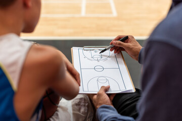 Fototapeta premium Coach discusses basketball strategy with player using a clipboard.