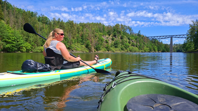 Woman kayaking enjoying summer vacation on mountain lake.