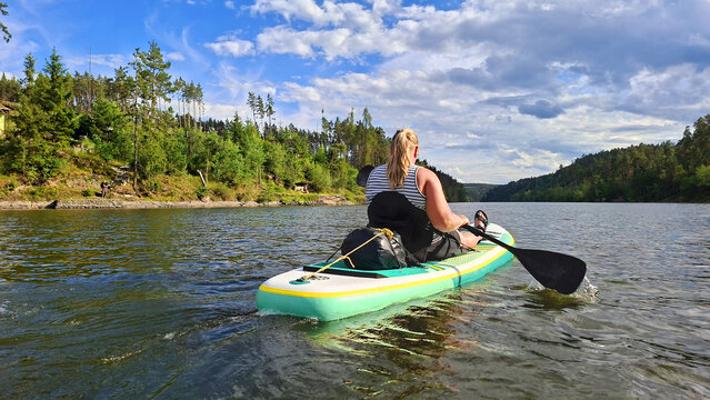 Woman kayaking enjoying summer vacation on mountain lake.