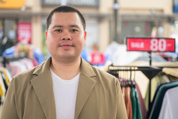 Obraz premium Plus size Isan Thai businessman at an outdoor clothing market looking at camera