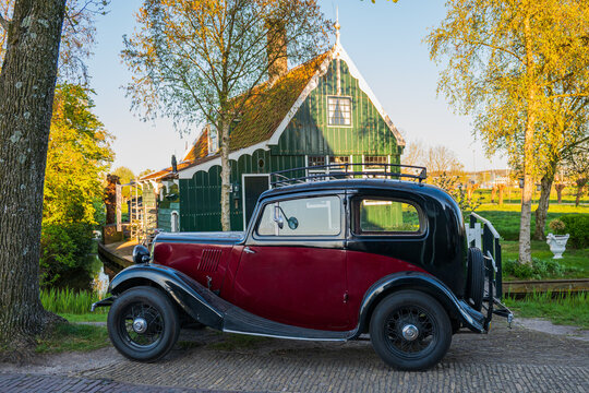 Amsterdam, Netherlands, 22.04.2026 - Vintage oldtimer car parked in front of traditional green Dutch house during golden hour
