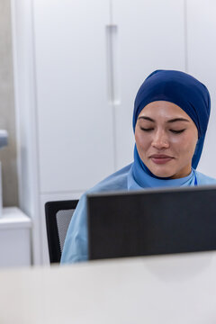 Adult woman sitting behind computer monitor at reception counter in medical clinic, copy space