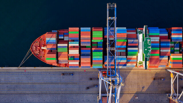 Large container ship docked at a commercial port, featuring a gantry crane loading colorful shipping containers, symbolizing global logistics and intermodal transportation
