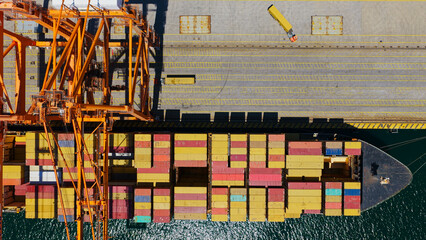 Large container ship docked at busy industrial port with gantry cranes and truck, aerial view capturing global logistics, cargo handling, supply chain and maritime transport operations © Nasos Zovoilis