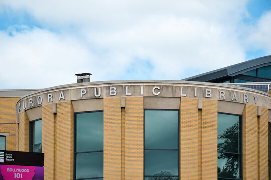 Close up view of the Aurora Public Library sign mounted on the exterior of a public library building in Aurora, Ontario, highlighting community services and civic infrastructure, June 2026