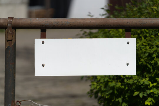leeres, wei&szlig;es, unbeschriftetes Schild mit Platz f&uuml;r eigenen Text an einem Zaun