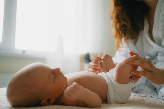 Newborn boy sleeping on a changing table with a mother gently holding his little feet, symbolizing infant care, bonding, and the beginning of family life