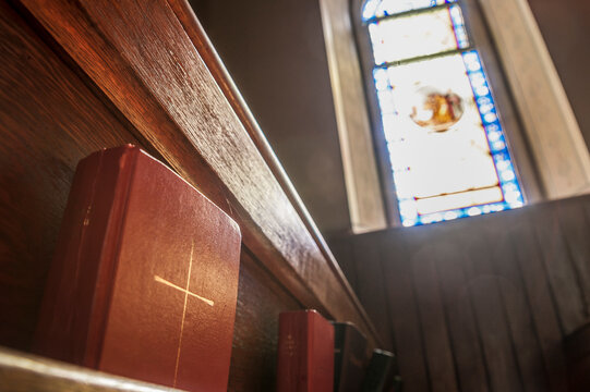 holy bible in pew with stained glass window