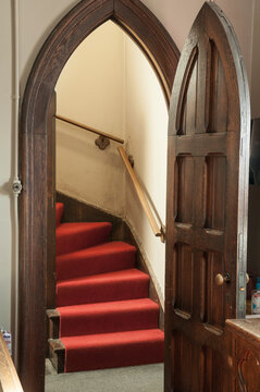 open door to stairwell with arched top wooden door