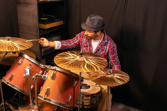 Concentrated man playing percussion instrument in a dark music studio, rock or jazz band concept