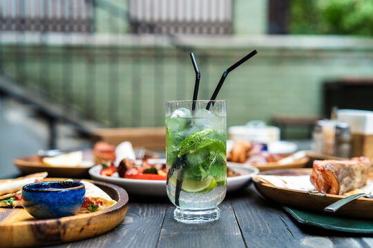 Refreshing summer mojito cocktail with ice and lime slices on an outdoor restaurant table