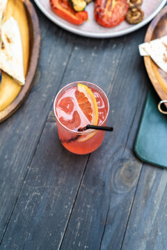 High angle view of a refreshing pink paloma cocktail on a dark wooden restaurant table