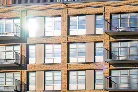 Modern apartment building facade with balconies and bright window reflection.