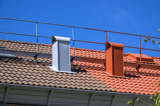 Colorful roof chimneys and safety railing against deep blue sky.
