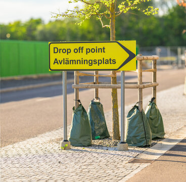 Yellow drop off point sign marking curbside urban pickup area.