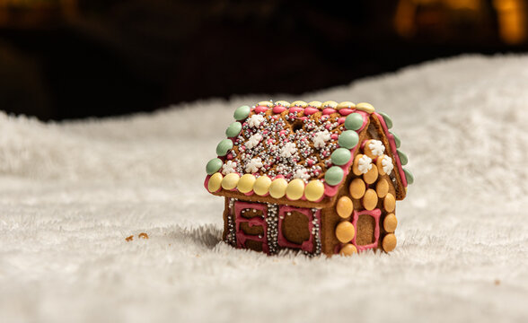 Gingerbread house on snow like surface with festive holiday decoration.