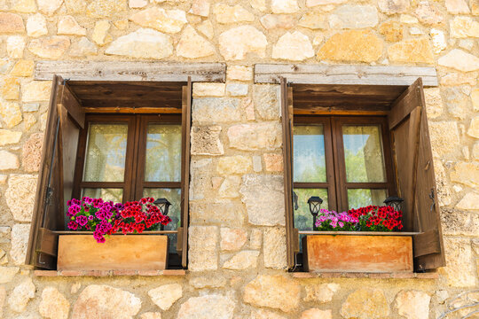 Stone house windows with colorful flower boxes on traditional medieval facade in Siurana village, Catalonia, Spain