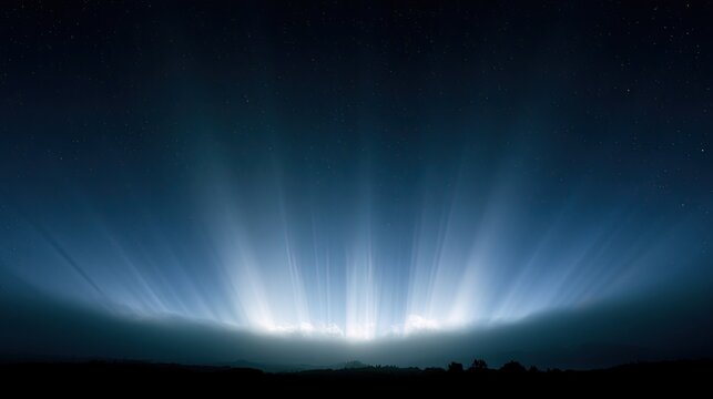 Radiant sky glows above dark, silhouetted landscape under starry night