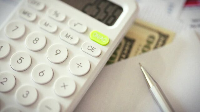 Accountant reviews financial figures on calculator, surrounded by cash dollars and scattered business papers on tabletop, illustrating precise cost control and accounting practices for small business