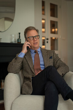 Mature businessman talking on mobile phone while sitting in hotel room