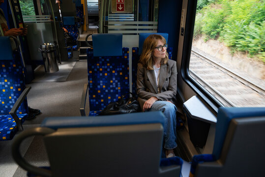 Businesswoman commuting by train and looking through window