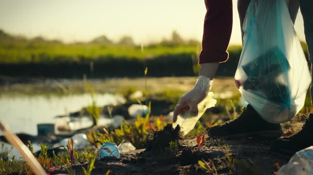 A human eco-activist manually separates plastic bottles and refuse outdoors in a natural area at sunset to promote environmental sustainability through recycling