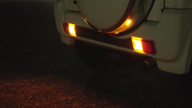 夜の道路でオレンジ色のライトを点灯させて停車する車の4K動画
