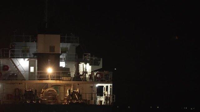 夜の港で照明に照らされる大型船舶のデッキと機械設備の4K動画
