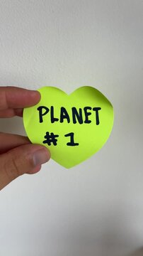 Hand holding heart shaped note saying planet number one