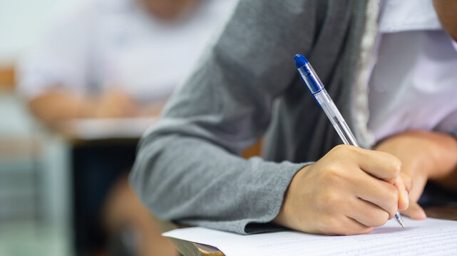 Close-up of Student Hand Writing on Exam Paper with Pen