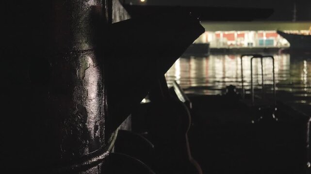 夜の港でライトに照らされる古い鉄製の構造物と背景に広がる水面反射の4K動画
