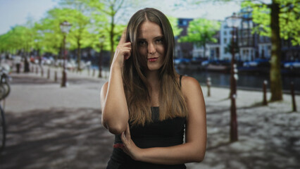 Fototapeta premium Young woman with crossed arms and finger to temple posed in a studio with canal backdrop and subtle expression; confidence.
