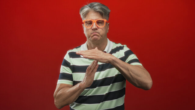 Man forms time out t with hands showing bare forearms and orange glasses in studio; boundary stop determination.