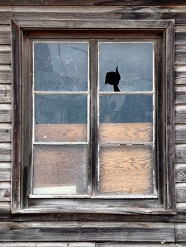 Weathered wooden window with cracked glass and boarded lower panes