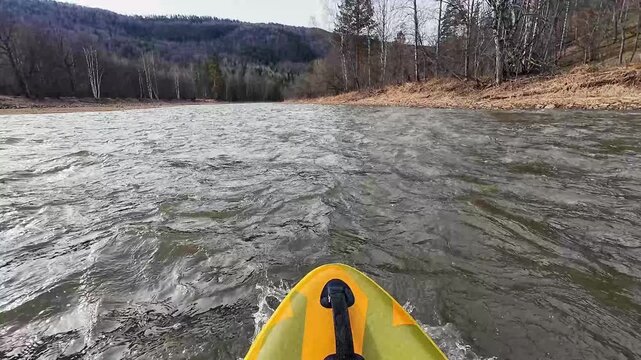 Calm river voyage. Yellow kayak on peaceful waters. Serene scenery of paddler on gentle river. Kayaker in yellow boat gliding over tranquil wide stream with distant hills