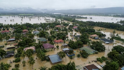 Obraz premium Severe flooding covers a rural tropical community with murky water, showing the devastating impact of extreme weather and climate change.