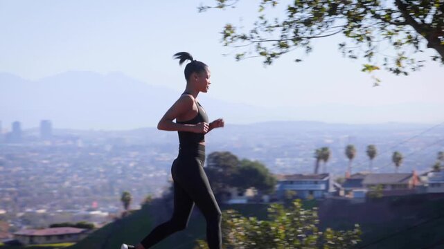 Mixed ethnicity (Asian-African) woman exercising in the park. The Los Angles skyline can be seen in the distance.