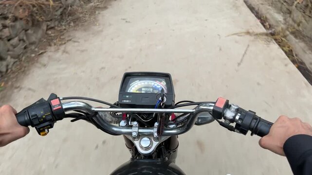Motorcycle ride view showing dashboard and handlebars on a narrow rural path.