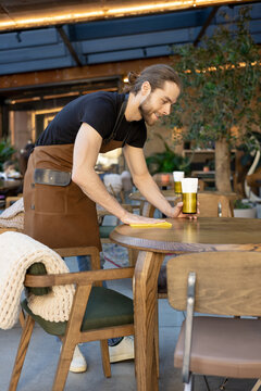 Young worker wiping table and preparing dining area
