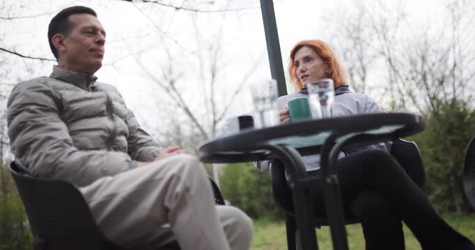 having coffee outdoors at a bistro on a cloudy morning in Eastern Europe while woman looks at her phone