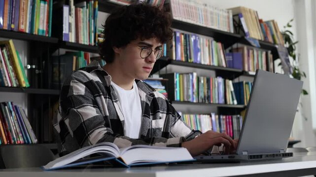 Focused teenage student using laptop during study session in library. Digital learning, STEM education, critical thinking, problem solving, concentration and academic development concept.