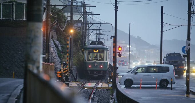 Tram on Wet Rail Coastal Street During Rain Storm In Japan